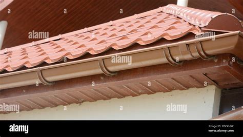 A Close Up On Red Metal Tile Rooftop With Wood Soffit House Eaves