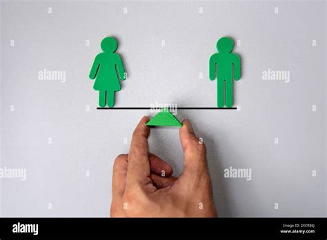 Hand Holding Wooden Triangle With Male And Female Human Figure On Balancing Scale Gender