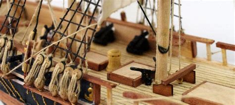 A Close Up Of A Model Ship With Ropes