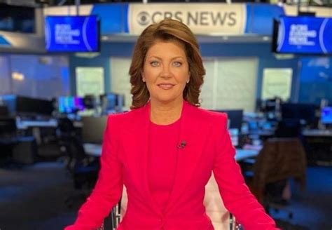 a woman in a red suit is sitting at a desk with her hands on her hips