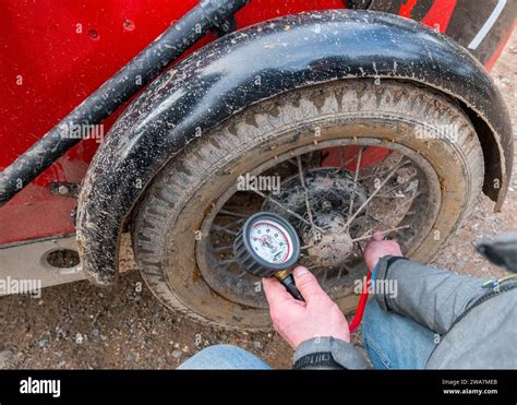 Drive Or Competitor Checking The Tyre Pressure On A Pre War Austin