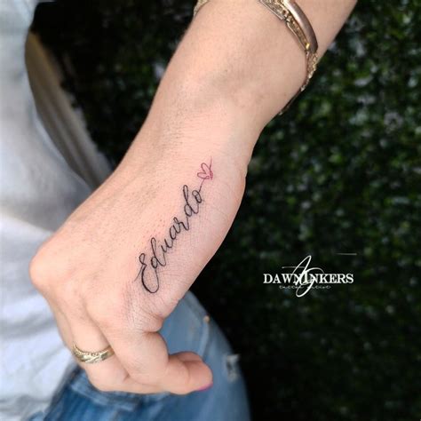 A Person With A Tattoo On Their Wrist Holding The Hand Of Another