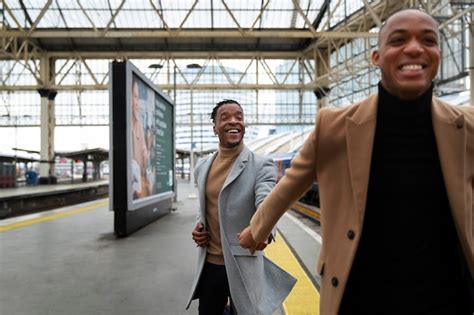 Casal gay de mãos dadas na estação de trem durante um encontro Foto Grátis