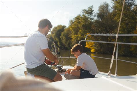 Young Caucasian father teaching his son to tie sail knots Stock Photo by StockRocketStudio