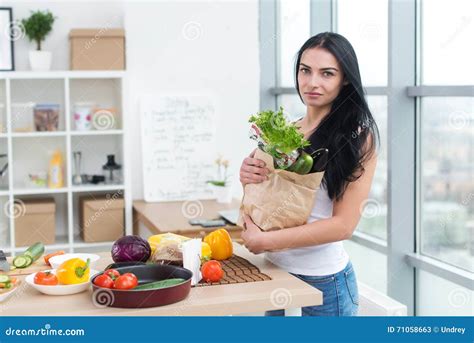 Seriously Looking Girl Holding Paper Bag From Market Full Of Green