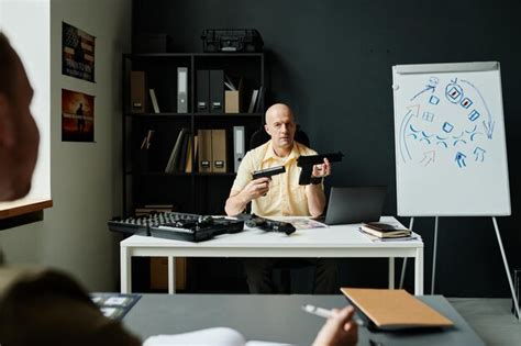Premium Photo Confident Mature Male Coach Comparing Two Guns At Lesson