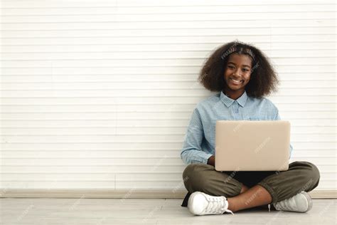 笑顔の肖像黒人アフリカ系アメリカ人かわいい学生小さな女の子の子供が床に座ってテクノロジーラップトップコンピューターを使用してキーボードで入力し