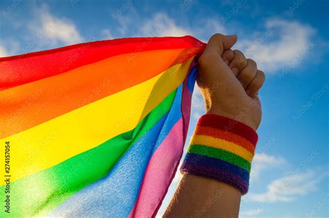 Hand With Rainbow Wristband Waving Gay Pride Flag Waving Backlit In The