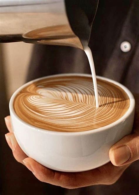 A Person Pouring Milk Into A Cup Of Coffee