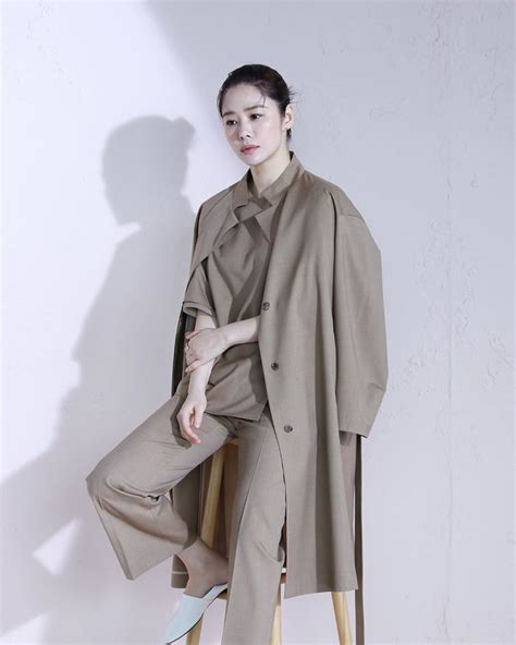 A Woman Sitting On Top Of A Wooden Chair Wearing A Coat And Matching