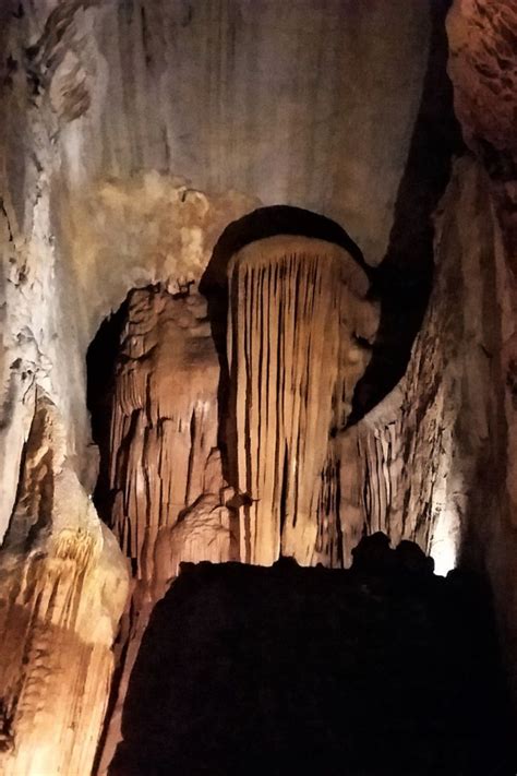 The Inside Of A Cave With Large Formations And Lights On Its Walls