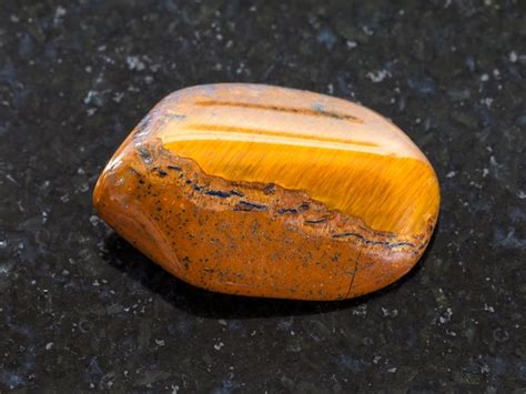 Piedra Preciosa De Ojo De Tigre Pulida Sobre Fondo Oscuro Foto Premium