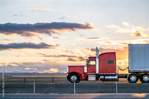 Side view of red big rig classic semi truck transporting cargo in dry ...