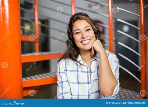 Exécutif Féminin De Sourire S asseyant Sur L escalier Dans Le Bureau