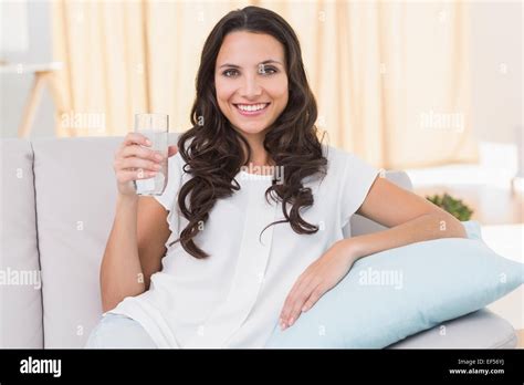 Pretty Brunette Drinking Water On Couch Stock Photo Alamy
