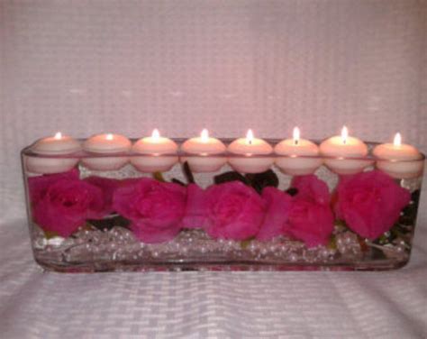 Pink Roses And Candles Are Arranged In A Clear Vase