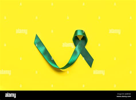 Green ribbon on yellow background. Liver cancer concept Stock Photo - Alamy