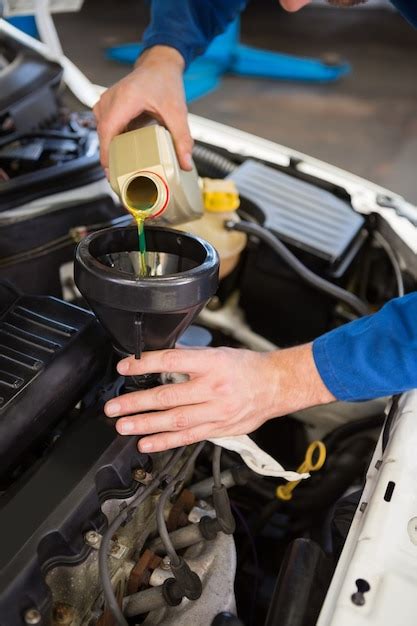 Premium Photo Mechanic Pouring Oil Into Car