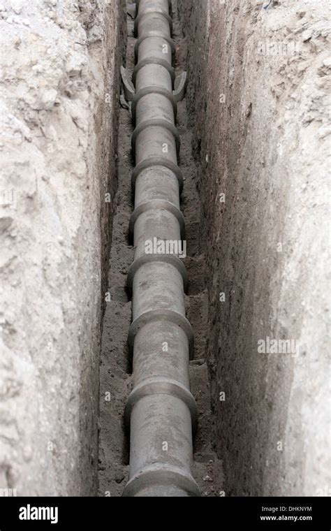 A gray concrete sewer pipe lying in a trench in a road at a ...