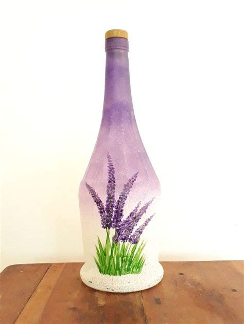 a purple vase sitting on top of a wooden table next to a white wall with grass painted on it