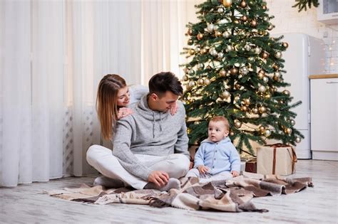 Una familia con un hijo pequeño se sienta cerca de un árbol de navidad