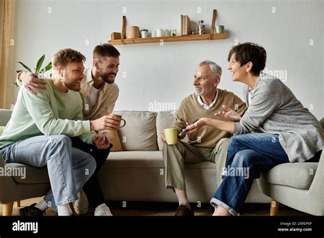 A Gay Couple Sits On A Couch With Parents Sharing A Warm And Happy Moment Stock Photo Alamy
