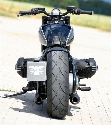 The Front End Of A Black Motorcycle Parked On A Brick Road With Grass