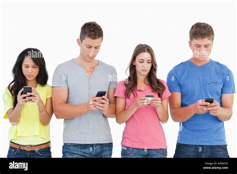 Four People Standing Beside Each Other And Texting On Their Phones