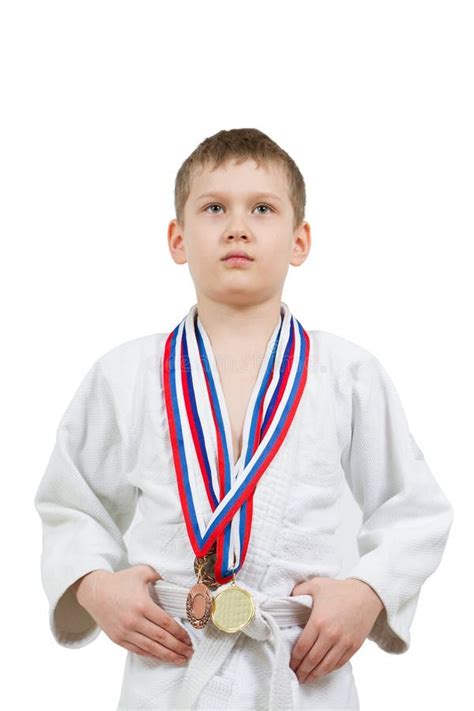 Muchacho Del Karate En El Kimono Blanco Con Luchar De Las Medallas Foto