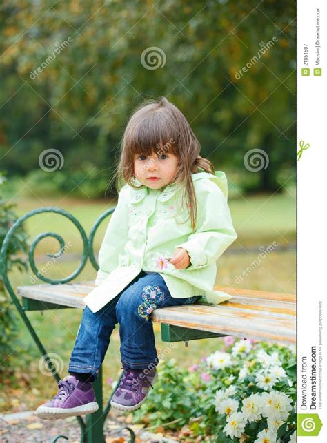 Petite Fille S Asseyant Sur Un Banc En Stationnement Image Stock