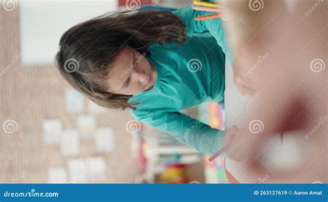 Adorable Chinese Girl Preschool Student Sitting On Table Drawing On