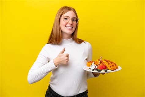 Mulher Jovem Ruiva Segurando Waffles Isolados Em Fundo Amarelo Dando