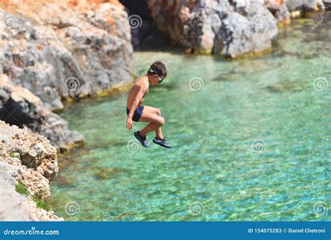 Little Boy Jumping Off Cliff Into The Ocean Summer Fun Lifestyle Stock