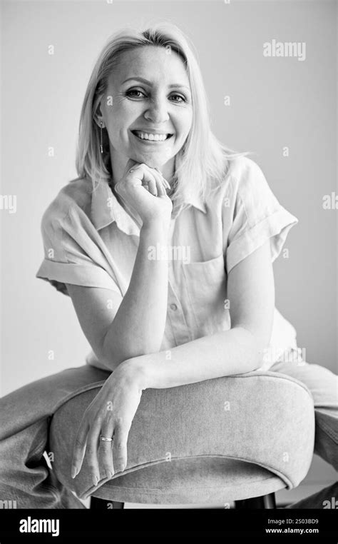 Pretty Female Relaxing On Bar Stool Portrait Of Woman With Blonde Hair Smiling Straight To