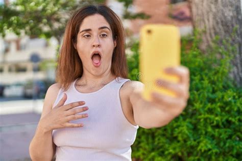 Brunette Woman Taking A Selfie Photo With Smartphone Scared And Amazed With Open Mouth For