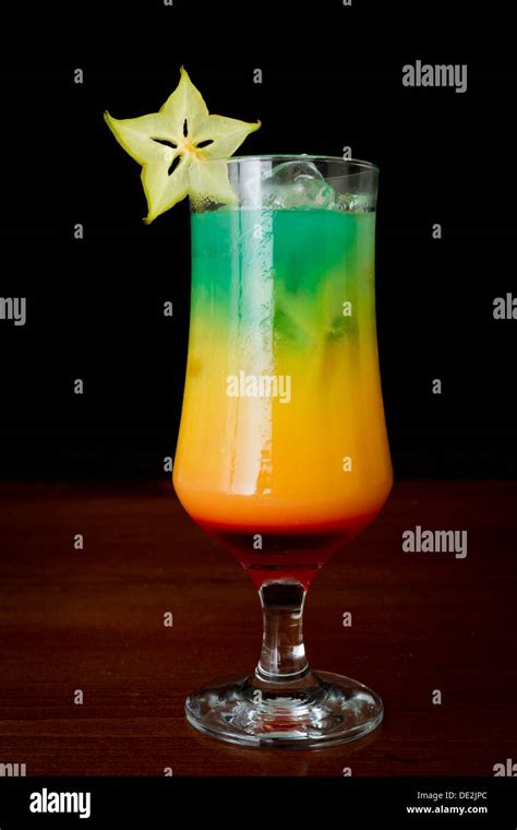 tropical drink served on a bar with a black background garnished with a ...