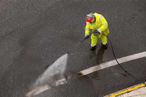 Premium Photo Worker Cleaning A City Road With High Pressure Water