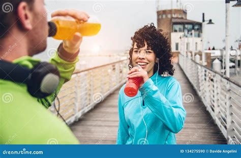 Man And Woman Drinking Energy Drink From Bottle After Fitness Sport