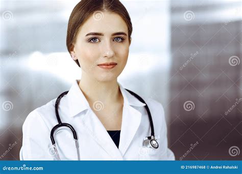 Friendly Female Doctor Standing And Holding Clipboard In Modern Clinic