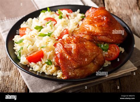 Portion Of Fried Chicken Thighs With Garnish Of Rice With Vegetables On