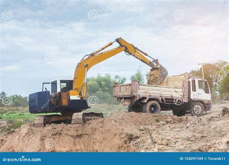 Yellow Excavator Machine Loading Soil Into A Dump Truck At Construction