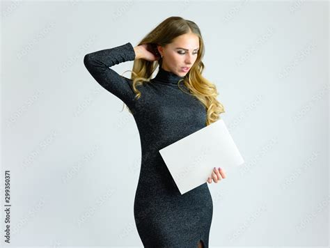 Portrait Of A Pretty Blonde Secretary Girl With Long Curly Hair In A Gray Dress Standing In The
