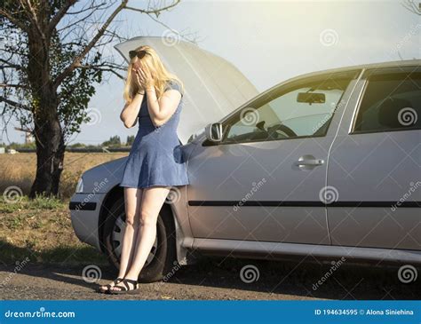 A Blonde In A Blue Sundress Votes On The Road Near Her Car An Open Bonnet Indicates A