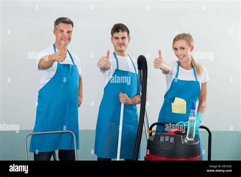 Group Of Happy Janitors With Cleaning Equipments Showing Thumb Up Sign