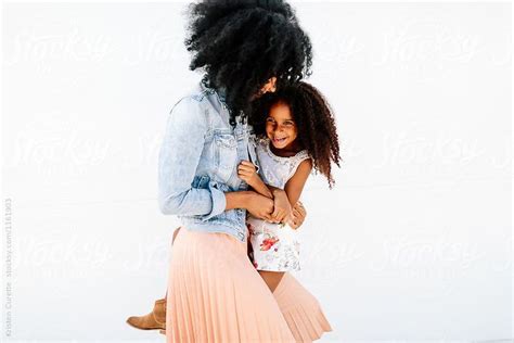 A Mother Holding And Swinging Her Young Daughter Against A White Background And Making Her Laugh