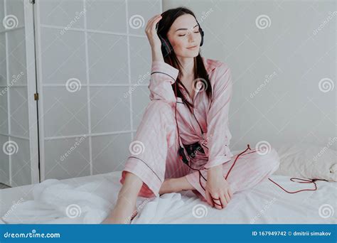 Woman In Pink Pajamas Listening To Music In Headphones Dancing On The