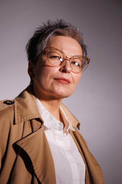 Premium Photo Portrait Of Stylish Mature Woman In Trench Coat And Eyeglasses Looking At Camera