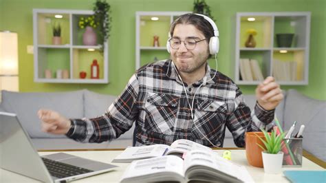 Cheerful and happy student is studying while listening to music ...