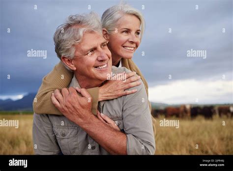 Mature Couple Embracing And Looking Happy While Bonding Outdoors At A Farm Carefree And Loving