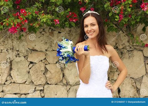 Jovem Mulher No Vestido De Casamento Que Levanta Na Frente Da Parede De